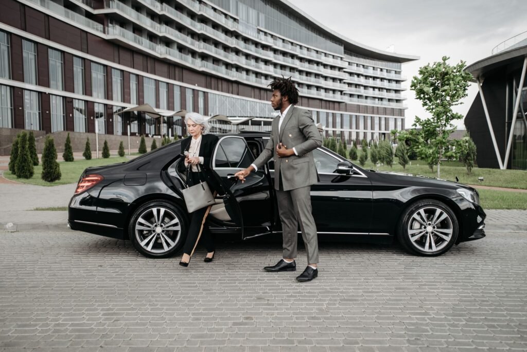 Chauffeur helping a client out of a black car