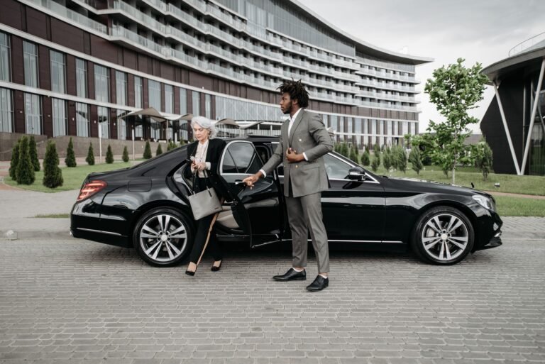 Chauffeur helping a client out of a black car