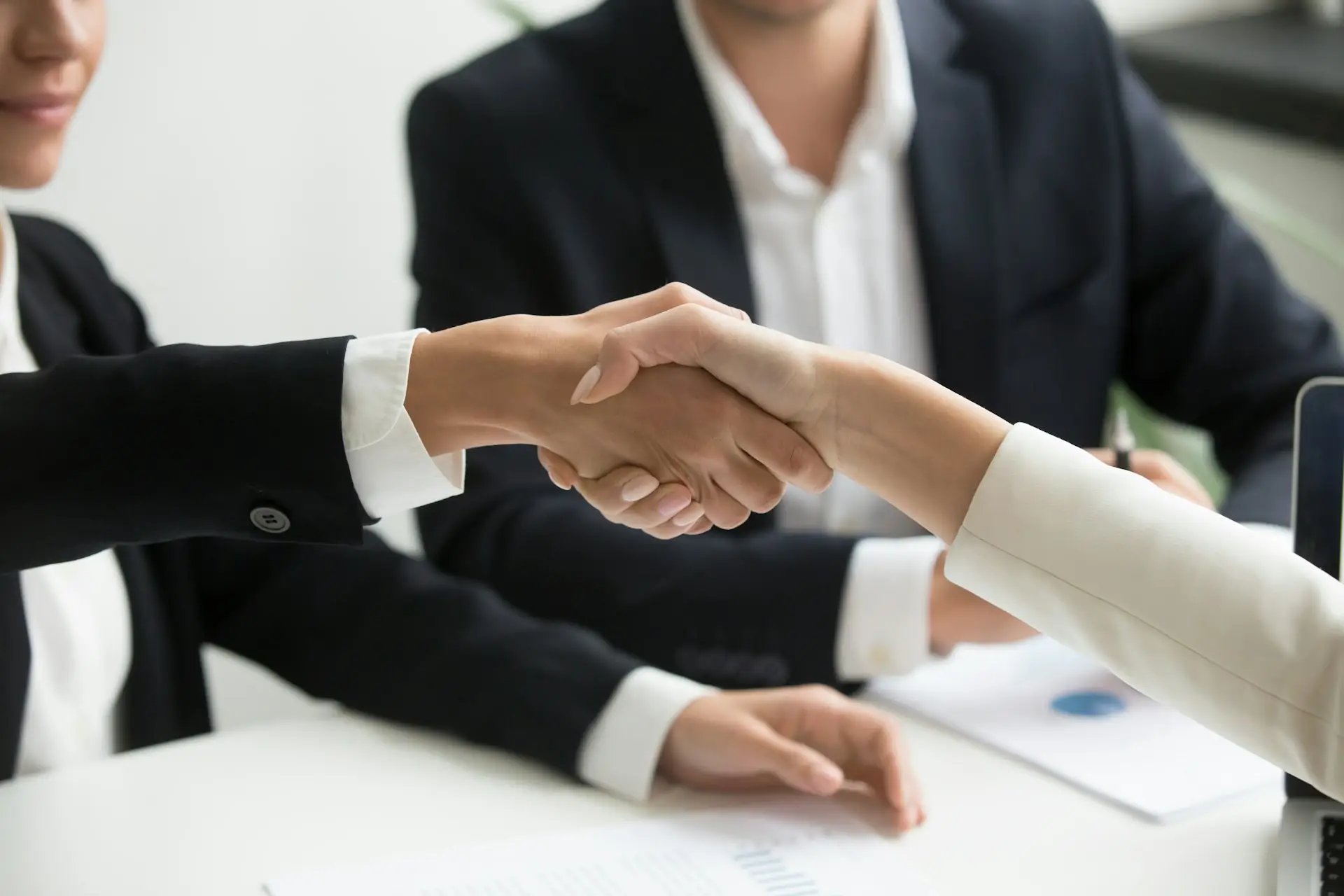 Two business people shaking hands across a desk