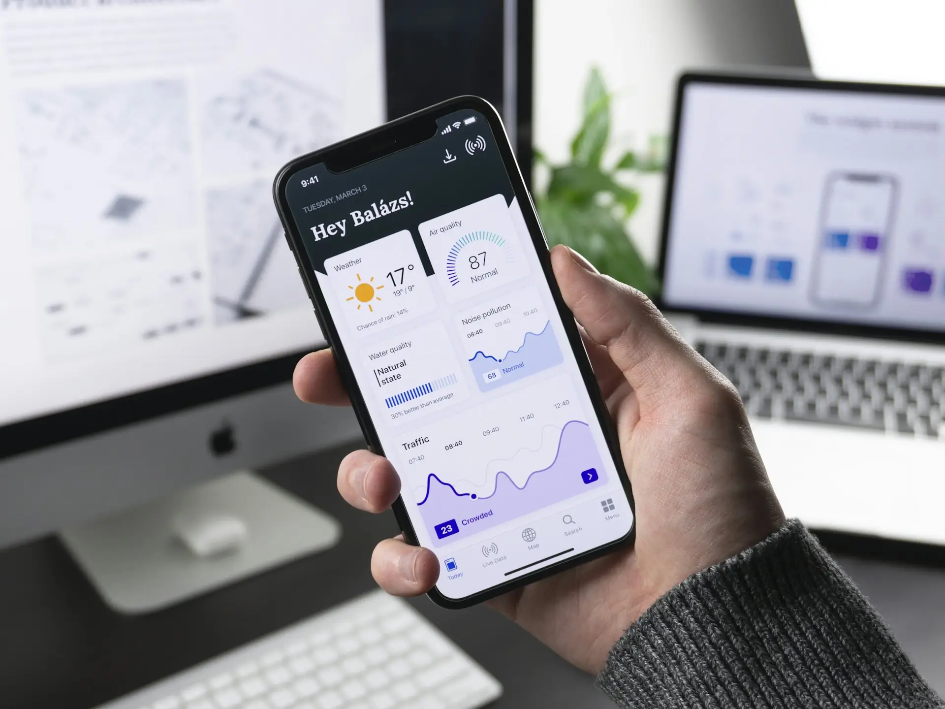 Hand holding a smartphone showing an app dashboard
