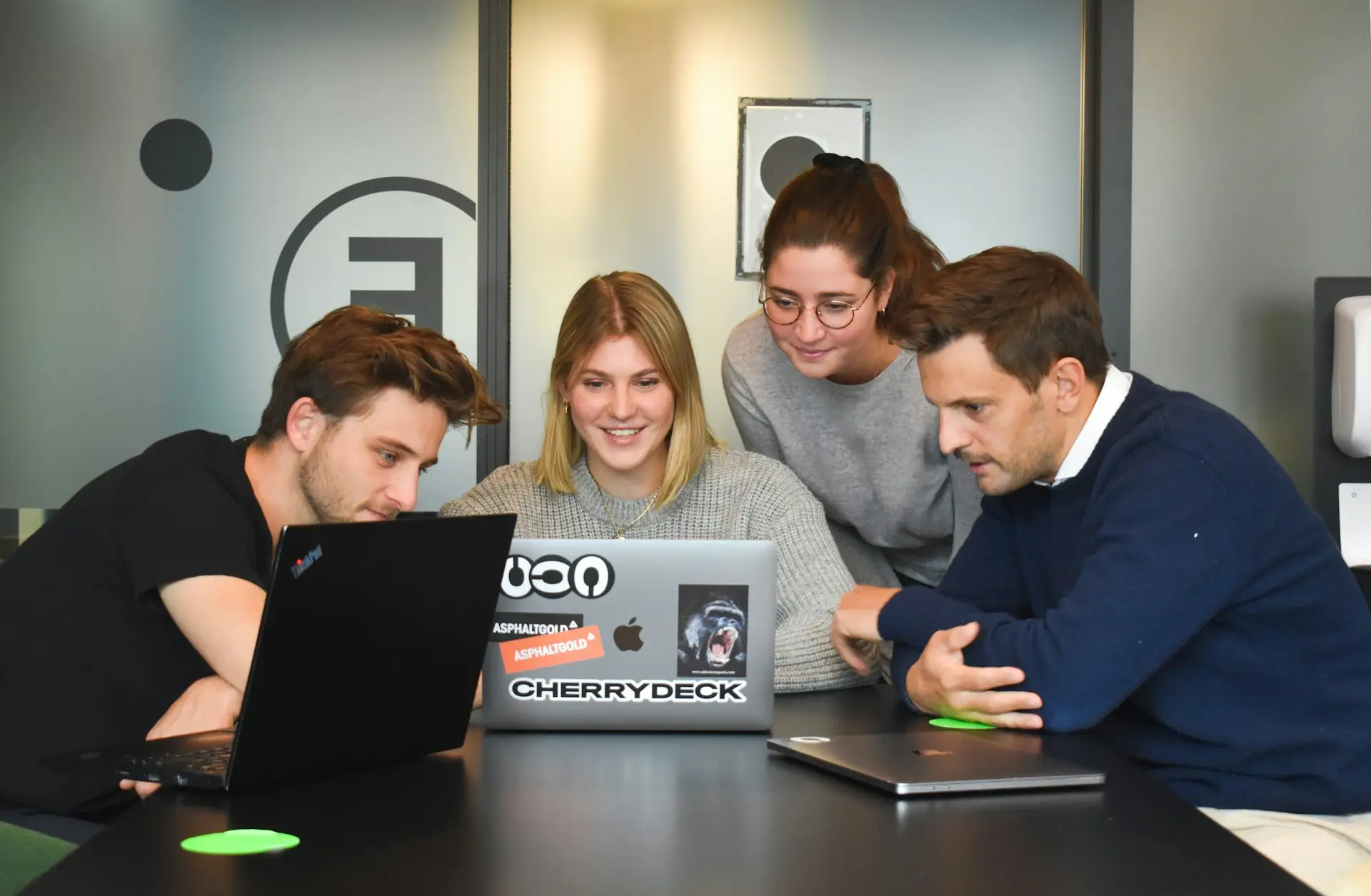 Four colleagues collaborating around a laptop in an office