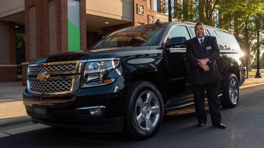Chauffeur standing beside a black luxury SUV