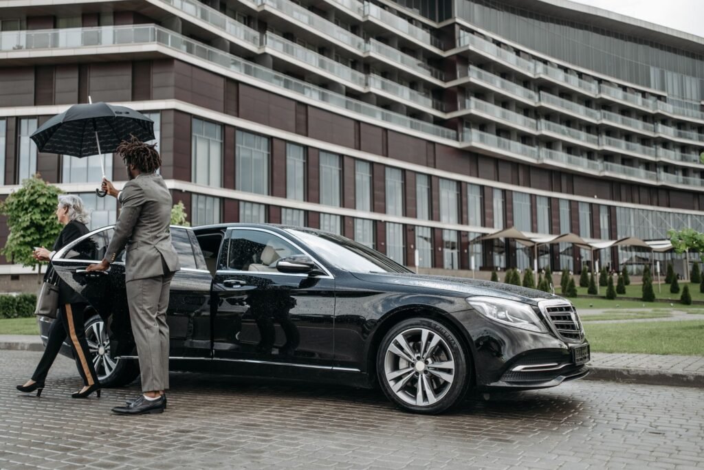 Client exiting a luxury car under an umbrella
